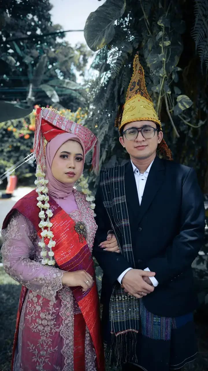 Pasangan pengantin berpakaian adat Batak menyambut tamu